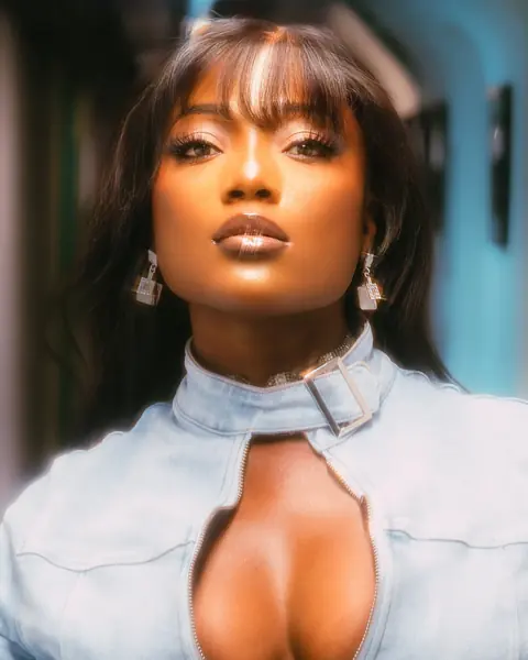 Efya in a denim jacket, hair loose, close to camera