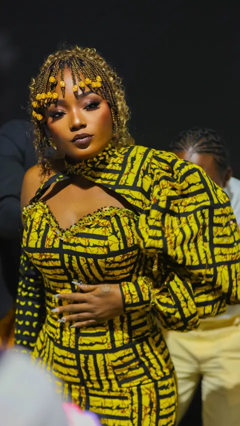 Efya in a yellow and black printed set, beaded hair