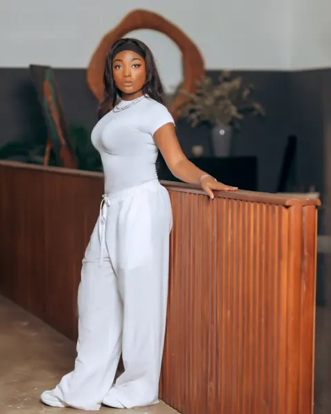 Efya in white, standing at a wooden counter