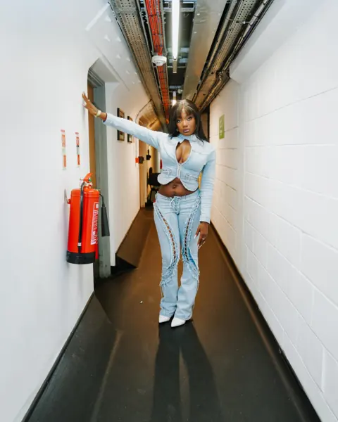 Efya in light denim in a backstage corridor